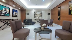 Una sala de estar moderna con una mesa de centro de vidrio, dos sillones marrones y un sofá.
