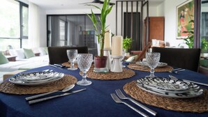 A dining table set with plates, cutlery, and candles, surrounded by chairs and a large window. - Your Private Villa Nestled in Nature (General Emilio Aguinaldo)
