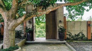 A building with a wooden door, potted plants, and a brick wall. - Your Private Villa Nestled in Nature (General Emilio Aguinaldo)