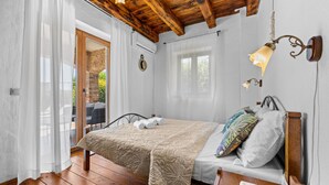 A bedroom with a wooden bed, a bedside table, a nightstand, a lamp, and a window with curtains. - Villa Lara with Private Pool near Pula (Čabrunići)