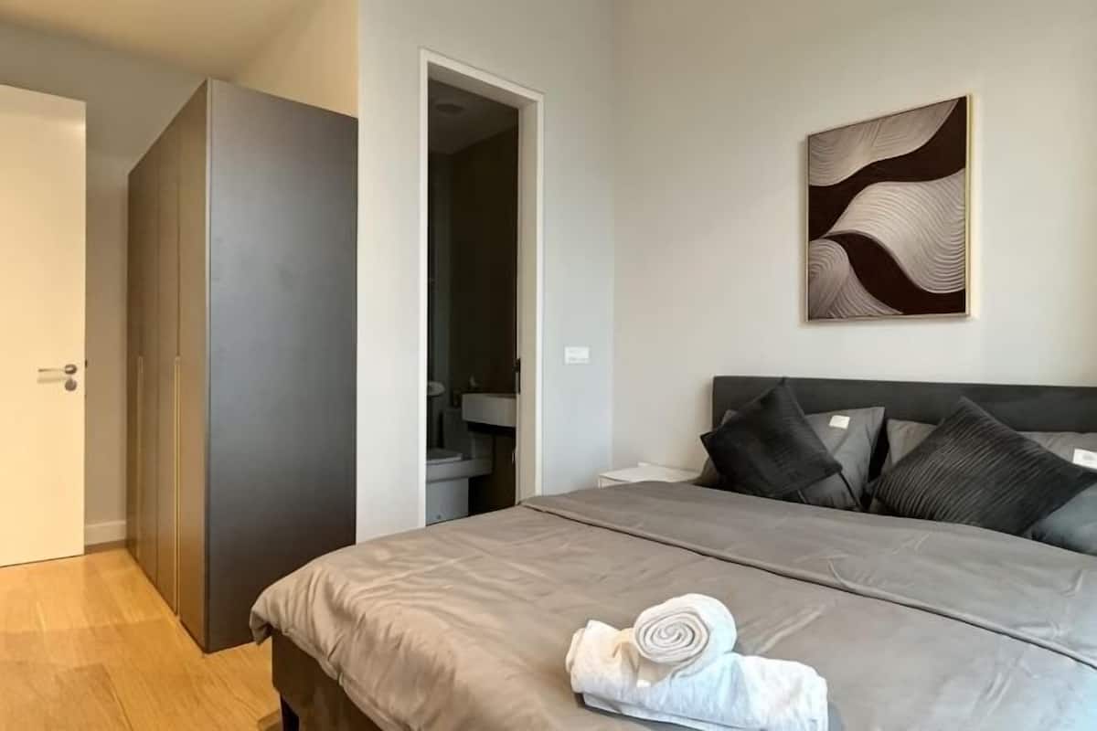 Een slaapkamer met een bed, een kledingkast, een badkamer en een aan de muur hangend kunstwerk.