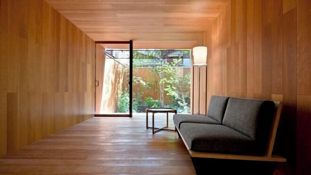 A modern interior with wooden paneling, a sofa, a small table, and a view through a glass door. - Kyo No Ondokoro Goshonishi #6 (Kyoto)