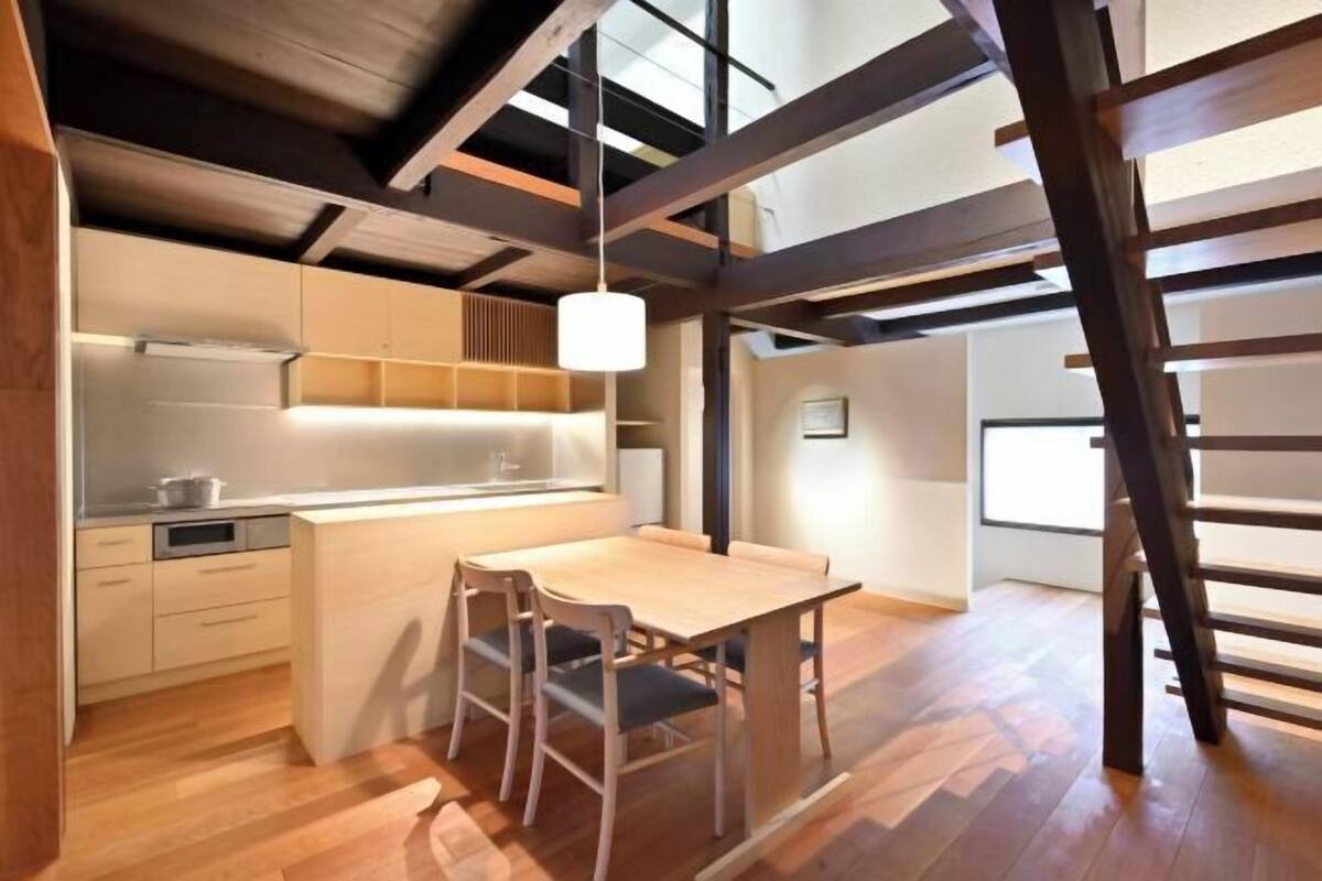 Eine moderne Küche mit Holzausstattung, einem Essbereich mit Tisch und Stühlen sowie einer Loft-Decke mit freiliegenden Balken.