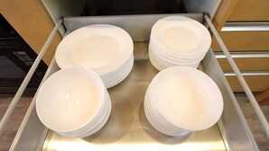 Une pile d’assiettes blanches dans un présentoir en acier inoxydable.