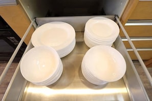 Une pile d’assiettes blanches dans un présentoir en acier inoxydable.