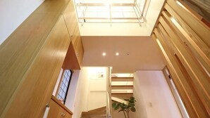 Un escalier avec des rampes en bois, une lucarne et une plante au centre.