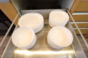 A stainless steel rack with stacks of white plates. - Crane Court KitaHorie (Osaka)