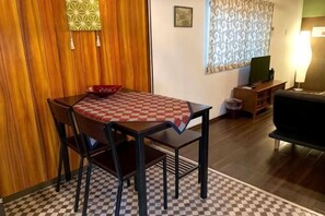 Un comedor con mantel a cuadros, paneles de madera, un televisor y un sofá.