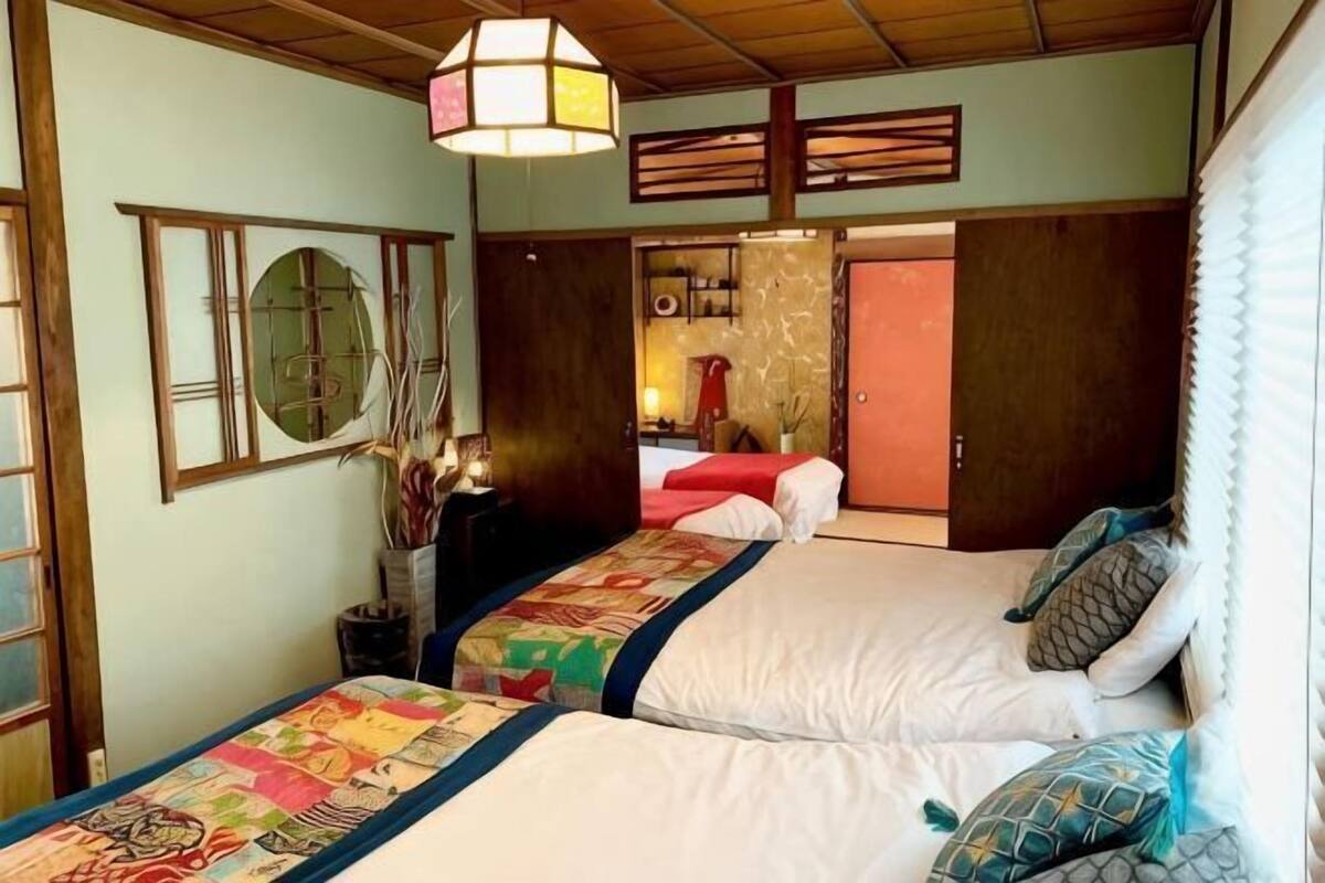 A traditional Japanese-style room with two beds, a hanging light fixture, and sliding doors.