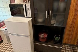 A kitchen with a refrigerator, microwave, and a cabinet with a glass door. - Tsukamoto Collector (Osaka)