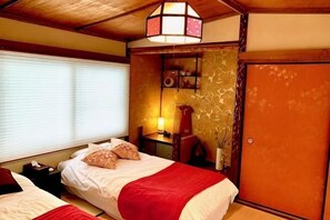 Habitación con dos camas, techo de madera, repisas con adornos y una puerta corrediza.