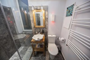 A bathroom with a glass shower enclosure, a white sink, a toilet, and a towel rack. - FlamingoHaven Chic&Renovated 1BRwBalcony PrimeSpot (Bucharest)