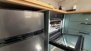 Una cucina moderna con frigorifero in acciaio inossidabile, forno integrato e piano di lavoro in legno.