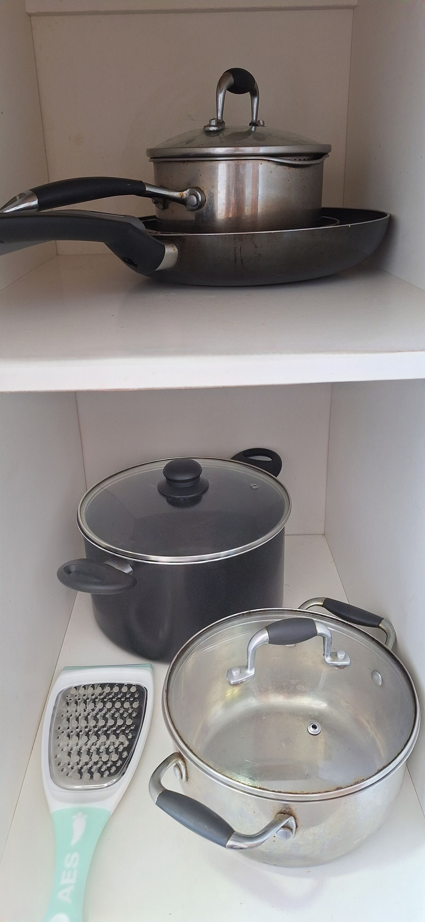 A kitchen with a stove, pots, and a grater on the countertop.
