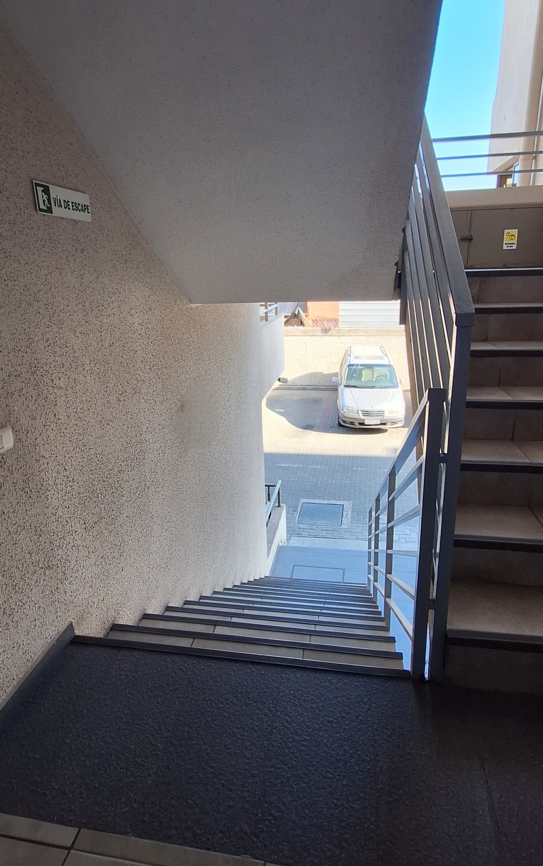 Un escalier menant à un espace extérieur où se trouve une voiture garée.