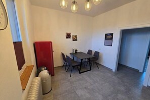 A compact dining area with a table and chairs, a red refrigerator, and a radiator. - LiFarm.de Apartments (Aerzen)