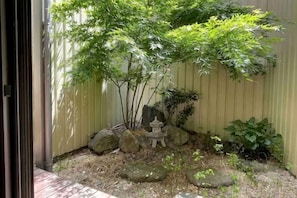 A garden with a small tree, rocks, and a stone lantern. - Shikai Family (101) (Osaka)
