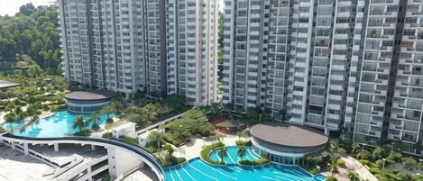 A high-rise residential building with multiple balconies and a large swimming pool area.