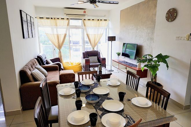 Un comedor con una mesa preparada para cuatro personas, un sofá, un televisor y una planta.