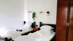 A hotel room with two beds, wooden headboards, a wardrobe, and wall-mounted shelves with decorative items. - Putrajaya Dwiputra 6 Plus 1 PAX Fully Air-Con (Putrajaya)