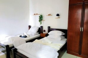 A hotel room with two beds, wooden headboards, a wardrobe, and wall-mounted shelves with decorative items. - Putrajaya Dwiputra 6 Plus 1 PAX Fully Air-Con (Putrajaya)