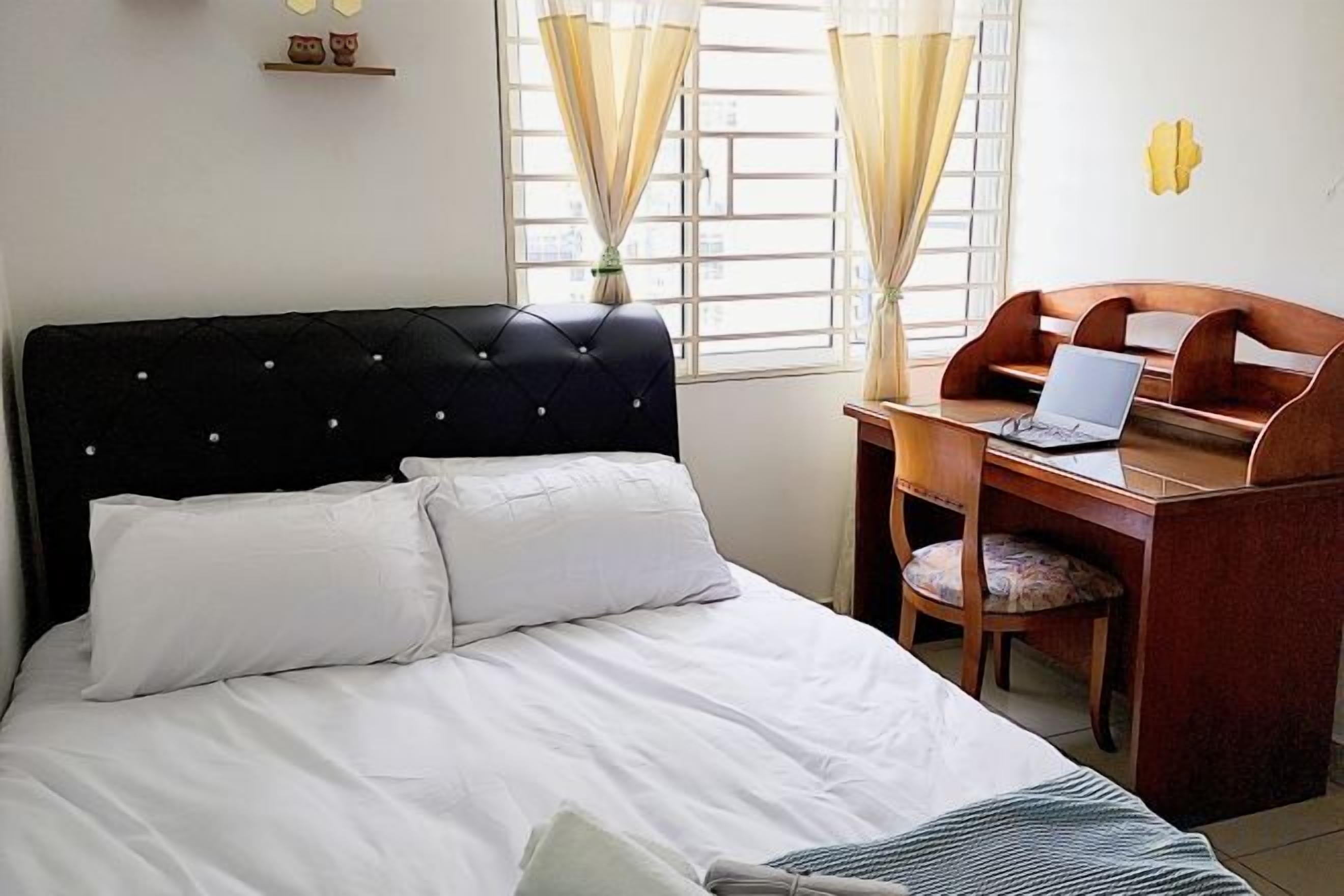 Une chambre à coucher avec un lit, un bureau avec un ordinateur portable et une chaise.