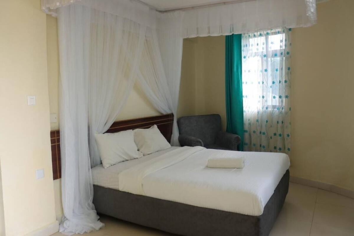 Een slaapkamer met een bed, een stoel en een raam met gordijnen.