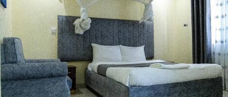 Un dormitorio con cama, una silla y una mesita de noche.