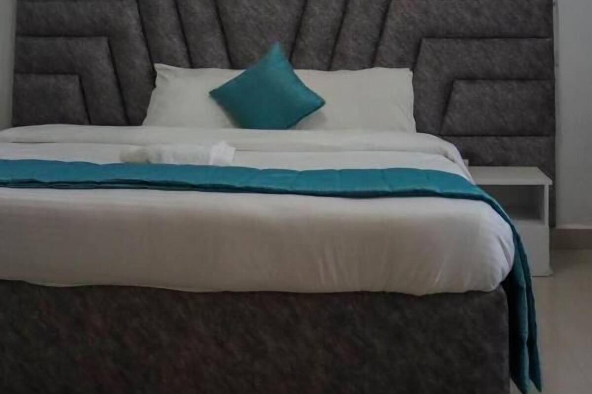 Een moderne slaapkamer met een groot bed, een geometrisch hoofdeinde en een dakvenster erboven.