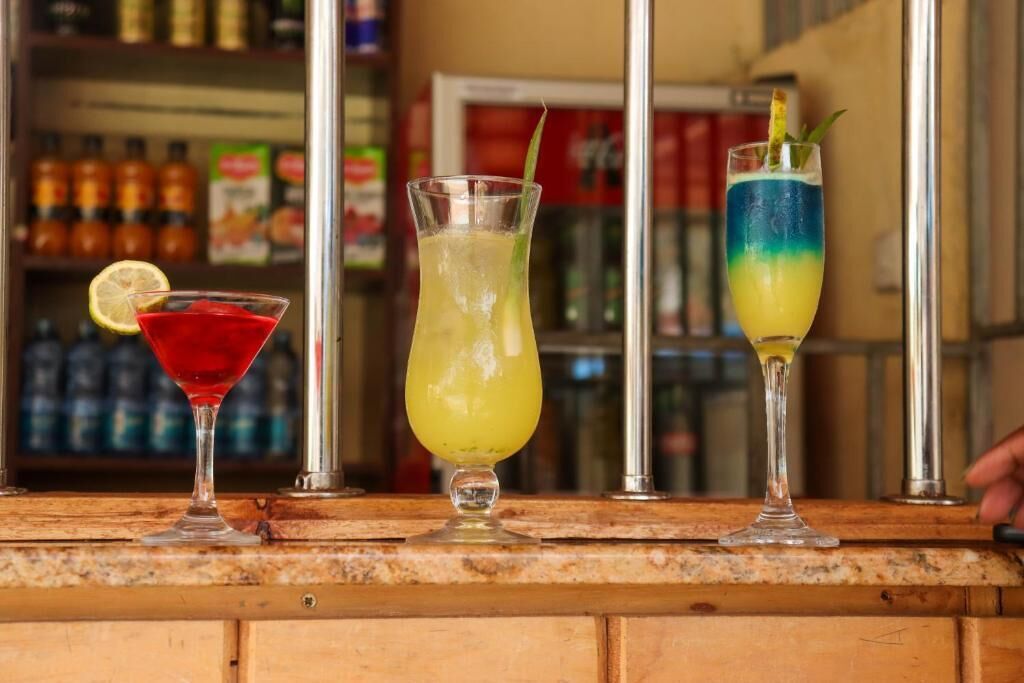 Three cocktails on a bar counter with a blurred background of shelves and products.
