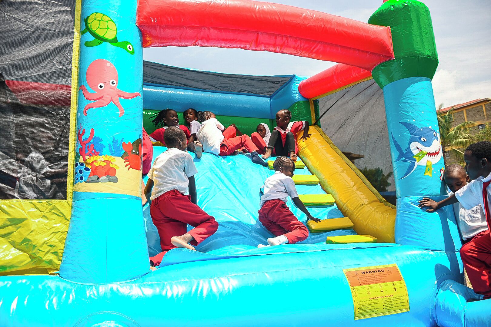 Un área de juegos inflable para niños con toboganes y escaleras de acceso.