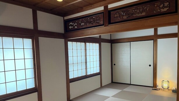 Egy hagyományos japán szoba, tatami szőnyeggel, tolóajtókkal és egy shoji-stílusú, papírral borított ablakkal.