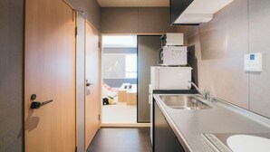 Une cuisine compacte équipée d’un réfrigérateur, d’un four à micro-ondes et d’un évier.