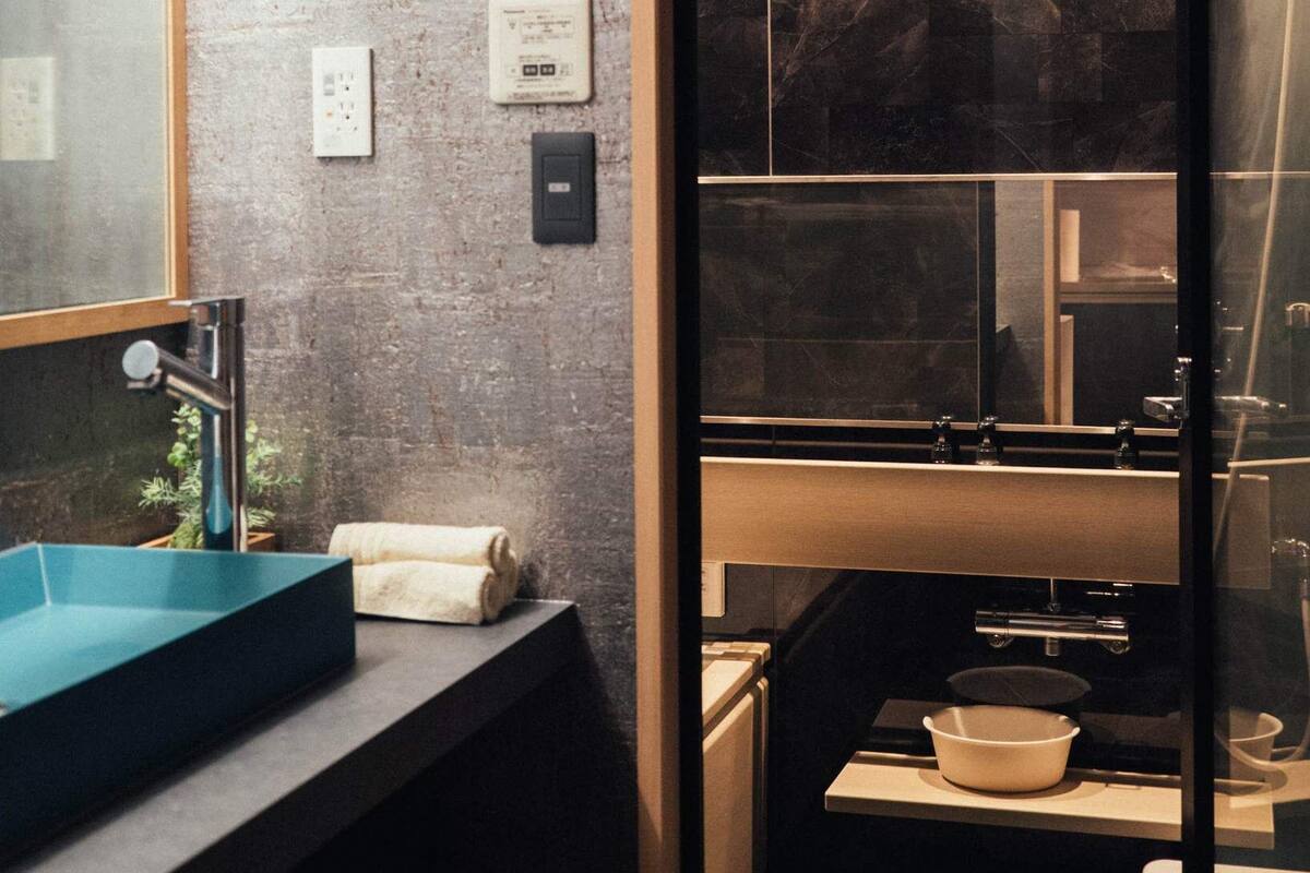 Une salle de bain moderne avec un grand miroir, un lavabo bleu, une serviette et un espace douche.