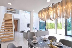 Un comedor moderno con una mesa de mármol, sillas grises y una lámpara de araña.