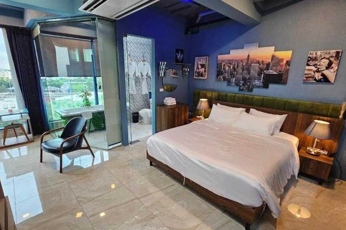 Een moderne hotelkamer met een groot bed, een stoel, een bureau en een balkon met uitzicht.