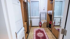 Ein kleines Badezimmer mit Waschmaschine, Heizkörper, Feuerlöscher und einem gemusterten Teppich.