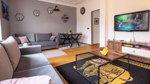 Ein modernes Wohnzimmer mit grauem Sofa, einem Couchtisch und einem Fernseher an der Wand.