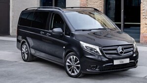 Ein schwarzer Mercedes Vito vor einem Gebäude mit großen Fenstern und einer Steinauffahrt.