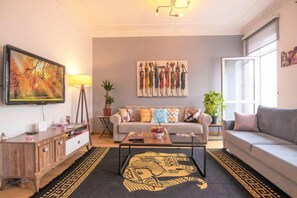 A living room with a sofa, coffee table, and artwork on the walls. - Gorgeous Two Bedroom Apartment - Roya (Istanbul)