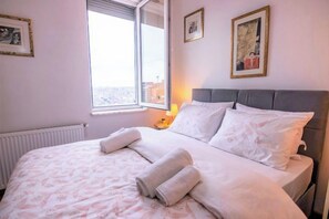 A hotel room with a large bed, a window with a view, and a nightstand with a lamp. - Gorgeous Two Bedroom Apartment - Roya (Istanbul)