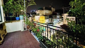 A balcony with potted plants and a view of the surrounding buildings at night. - Vietnam Travelers Home 1 with Private Balcony (Hanoi)