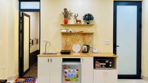 A compact kitchen with a built-in dishwasher, a microwave, and a small countertop area with decorative items. - Vietnam Travelers Home 1 with Private Balcony (Hanoi)