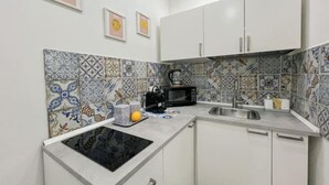 A compact kitchen with white cabinets, a black microwave, and a sink. - Ballaro's Vibe (Palermo)