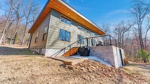 Une maison moderne à deux étages, dotée d’une terrasse en bois et de grandes fenêtres.
