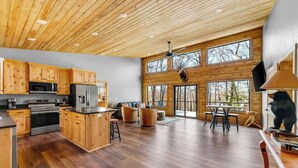 Una cocina amplia con armarios de madera, una isla central y un comedor con un ventanal grande.