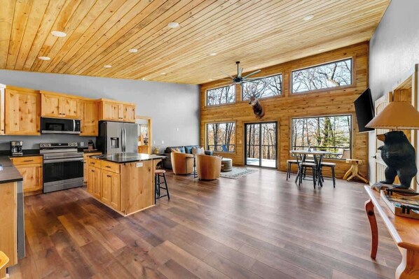 Una cocina amplia con armarios de madera, una isla central y un comedor con un ventanal grande.