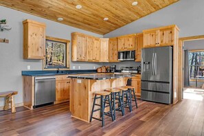 Una cocina moderna con armarios de madera, electrodomésticos de acero inoxidable y una isla central con taburetes de bar.