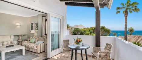 Un balcon avec vue sur la mer, un canapé, une table et des chaises.