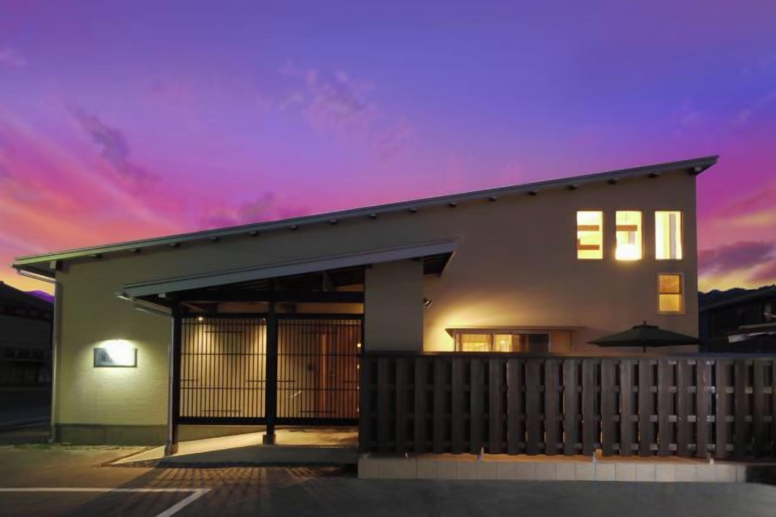 A modern building with a garage entrance, a covered patio, and a wooden fence.